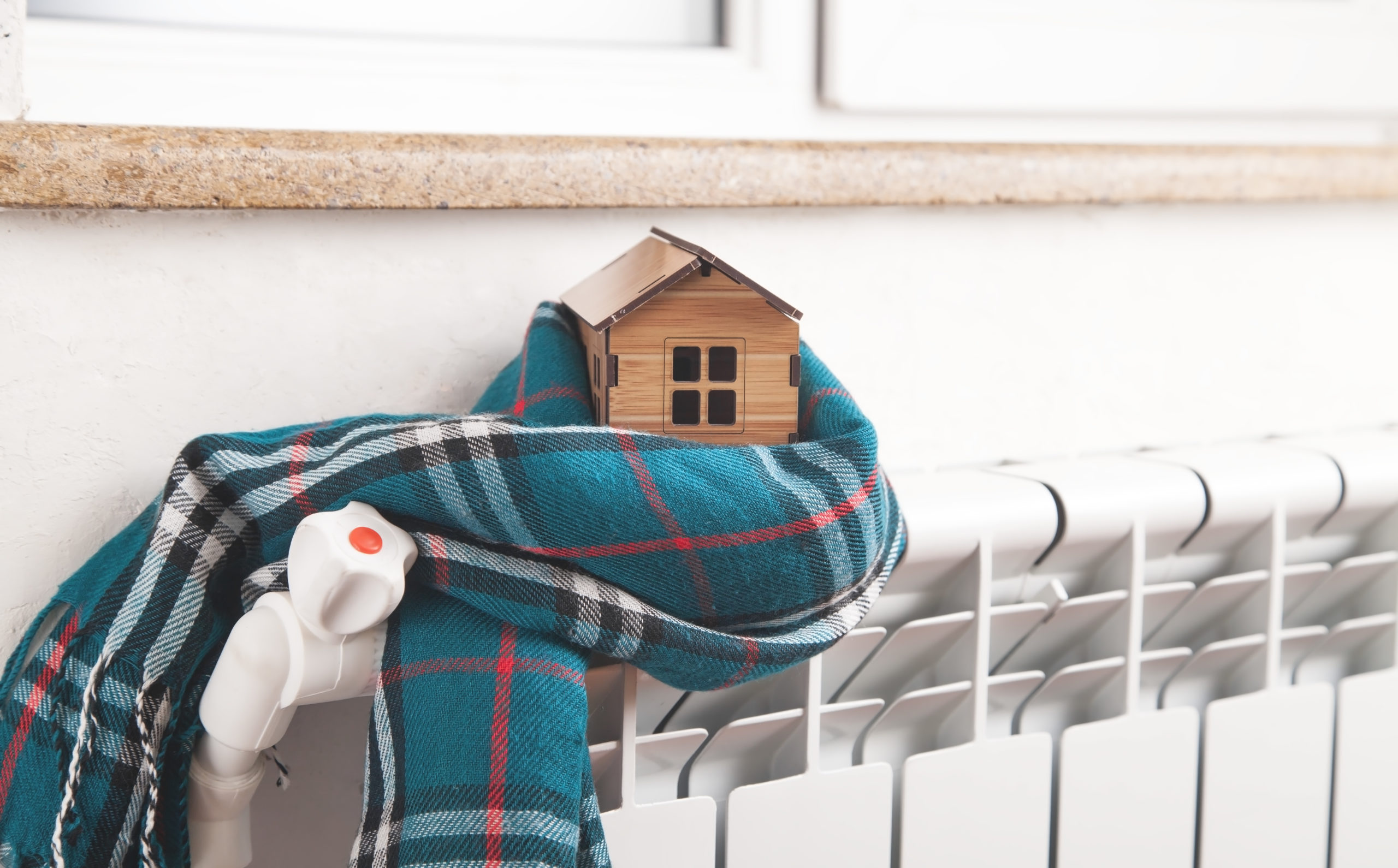 House model and scarf on radiator. Home. Winter. Energy. Efficie